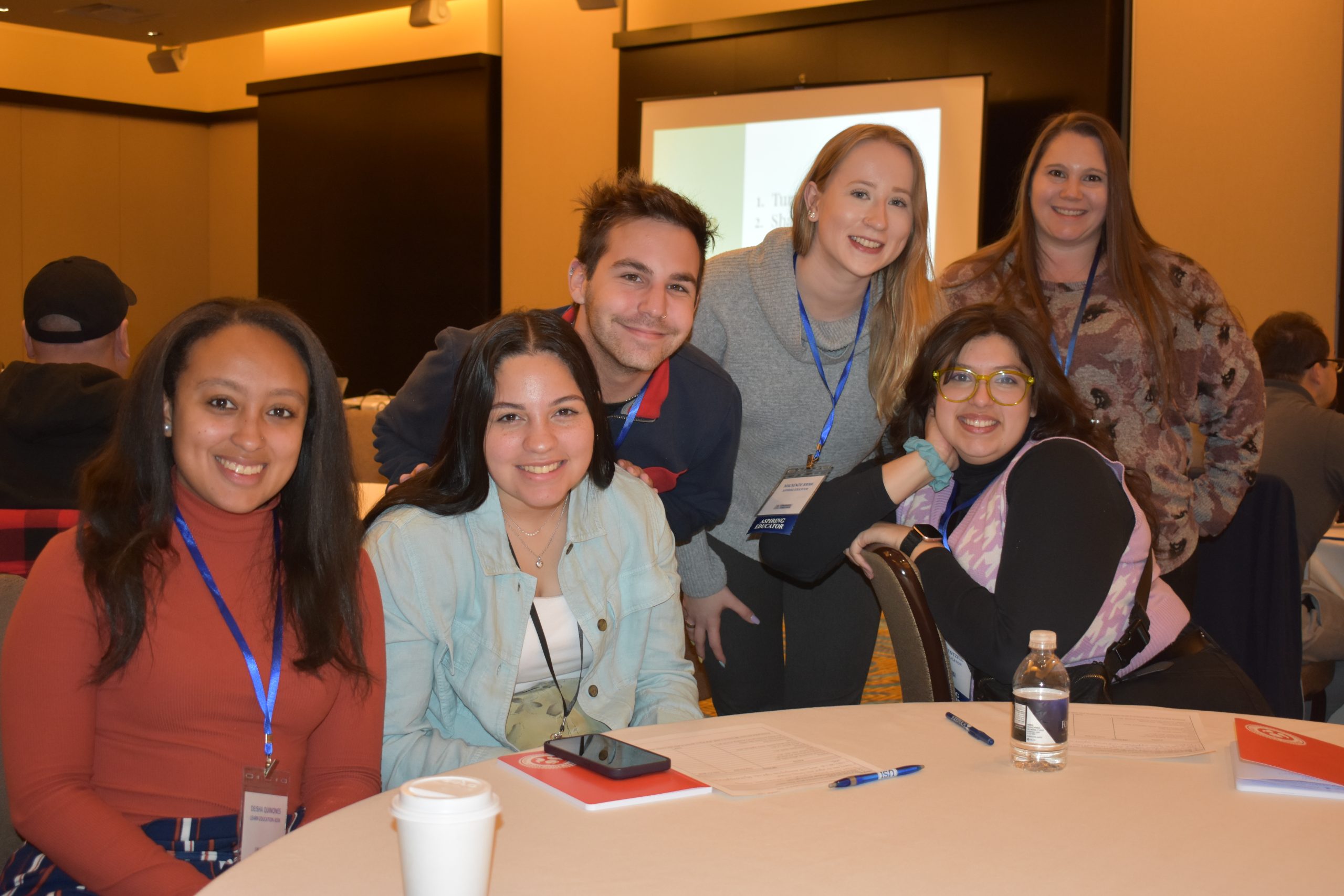 A group of new and aspiring educators attending CEA's Early Career Educator Conference pose behind a table in a workshop room.